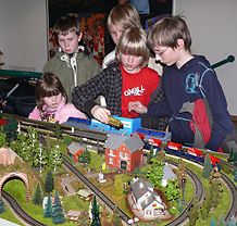 Fnf Kinder an den Trafos hinter einen kleinen Modellbahnanlage